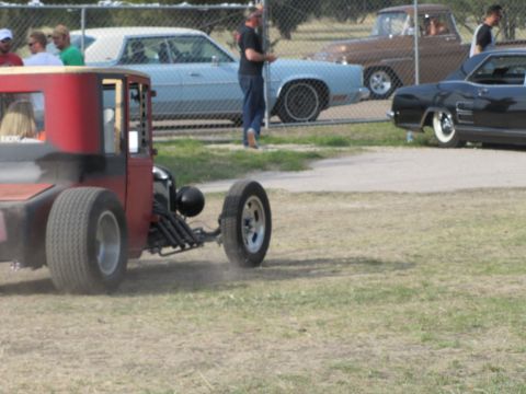 2006 BMW 5 Series - A custom hot rod is seen in motion, with other vehicles and spectators in the background.