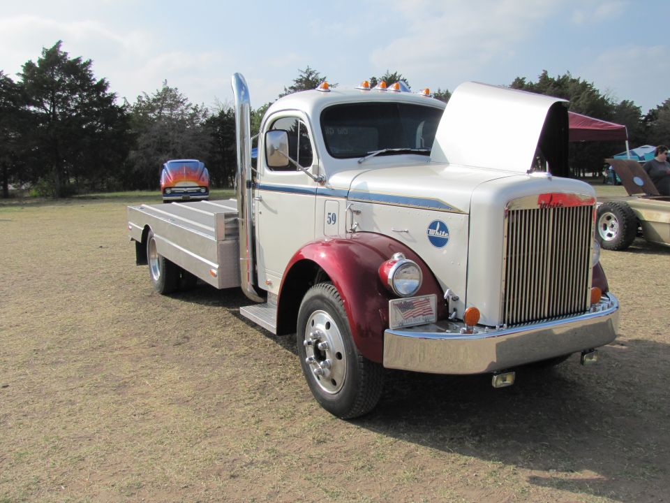 Vintage White truck with flatbed and a classic car in the background