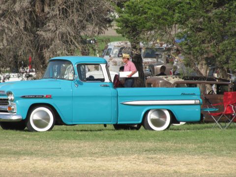 2006 BMW 5 Series - A turquoise Chevrolet pickup truck is parked on a grassy field with other vehicles in the background.