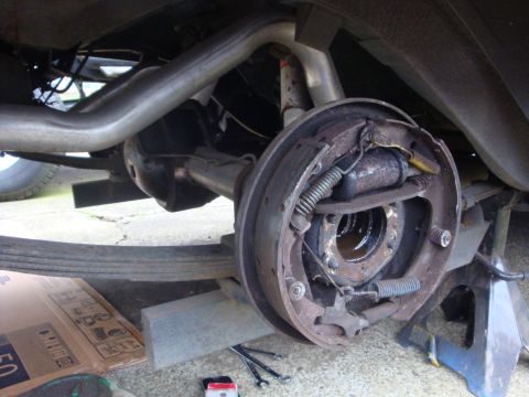 1964 Ford Fairlane - Close-up view of a vehicle's rear axle drum brake assembly, showing brake shoes and springs.