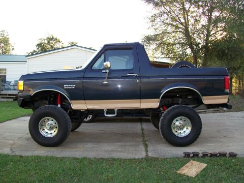 1990 Ford Bronco - This lifted Ford Bronco is shown from the side, a two-tone paint scheme and large off-road tires.
