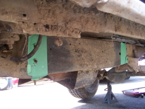 1989 Ford Bronco - The undercarriage of a 1989 Ford Bronco reveals green painted brackets and suspension parts.