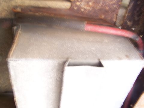 1989 Ford Bronco - A close-up view of a vehicle's battery box and a red hose, with visible rust on the chassis.