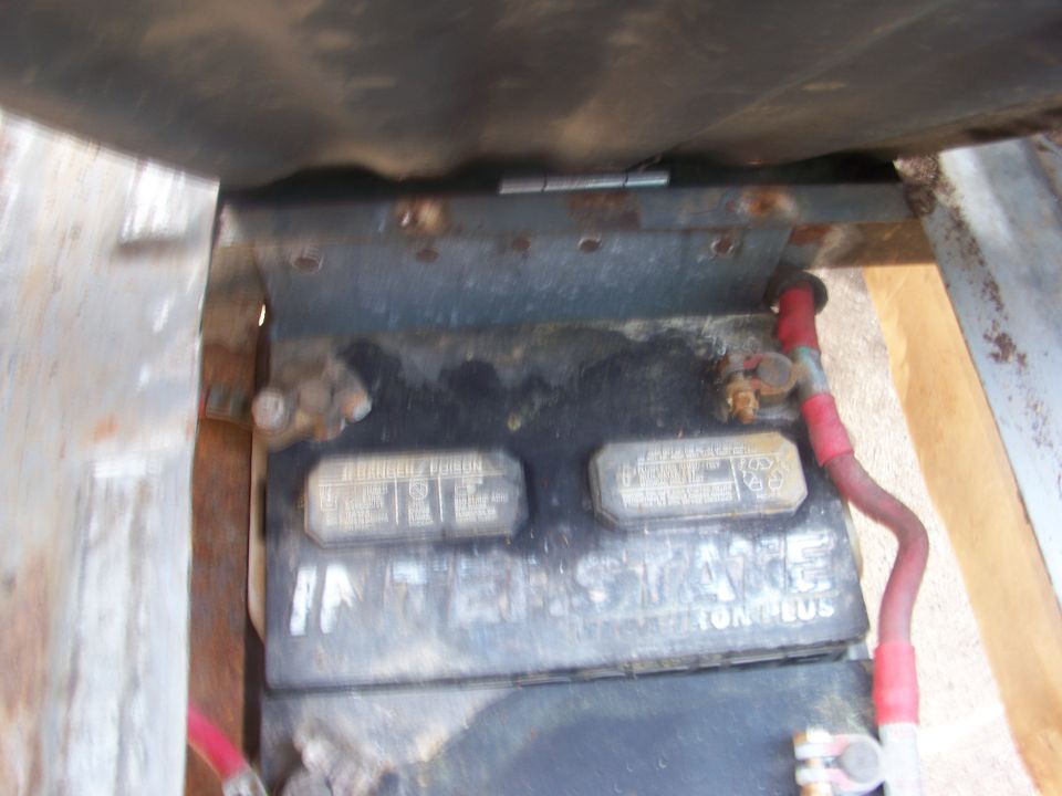 Car battery with red cables and corrosion, viewed from above