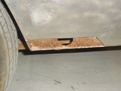 1971 Dodge Dart - Close-up of rusted metal panel with a cutout, showing part of a tire.