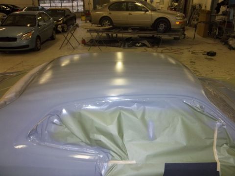 1971 Dodge Dart - A car's roof is covered in protective plastic and green paper, awaiting a fresh coat of paint in a repair shop.