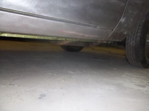1971 Dodge Dart - The undercarriage of a vehicle is shown from a low angle, revealing a spare tire and the concrete floor below.