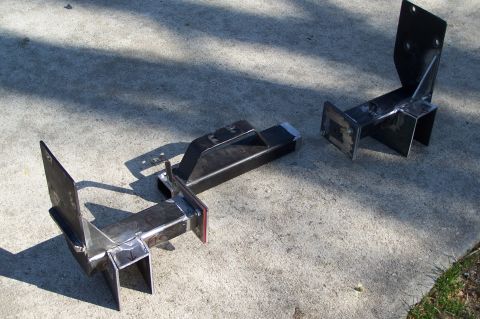 2000 Ford F-150 - Two custom-welded steel brackets are laid out on a concrete surface.