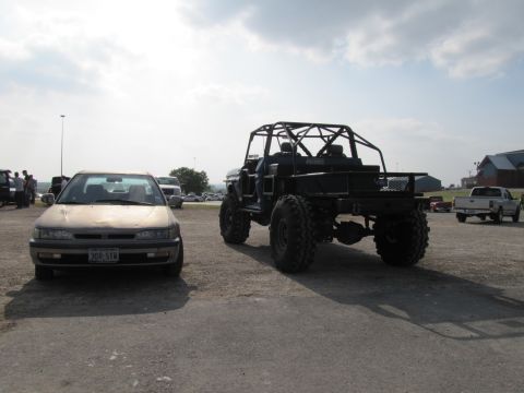 2006 BMW 5 Series - A custom buggy and a sedan are parked outdoors under a cloudy sky.