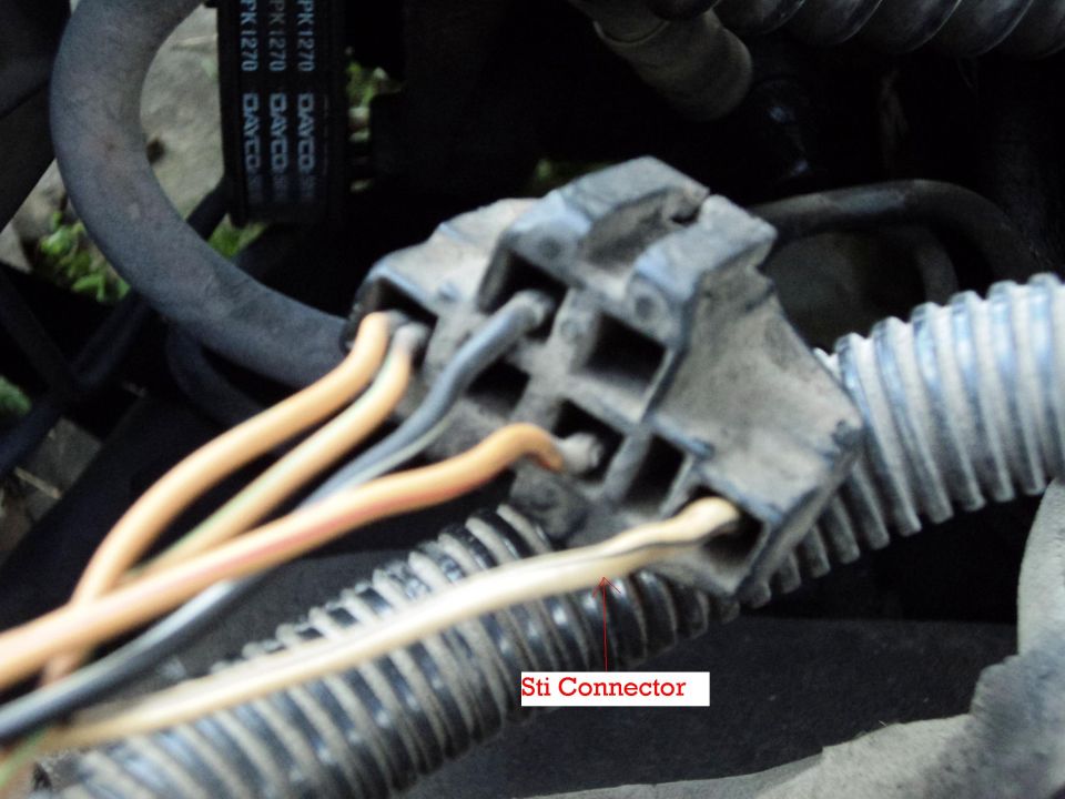 Close-up of a gray electrical connector with orange and black wires, labeled 'Sti Connector'
