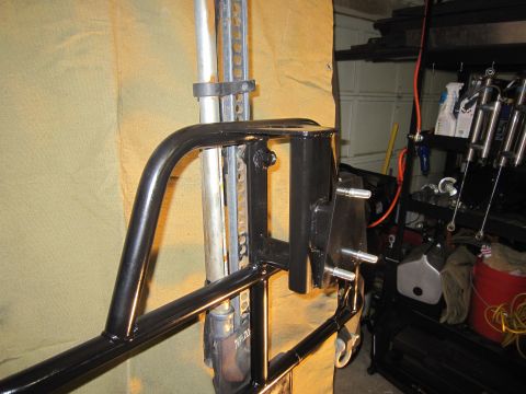 2008 Jeep Wrangler - Close-up of a black metal spare tire carrier mount with a jack secured to it.