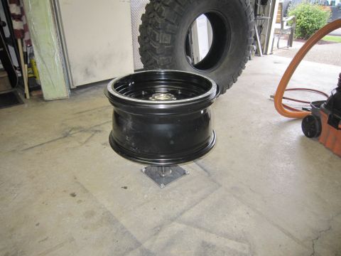 2008 Jeep Wrangler - A black aftermarket wheel and a large off-road tire are shown in a garage setting.