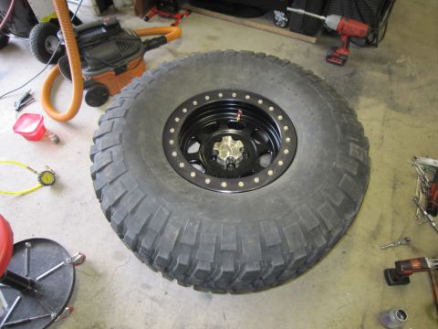 2008 Jeep Wrangler - A close-up of a large off-road tire and wheel assembly is shown in a garage setting.