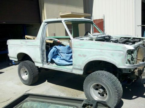 1995 Ford Bronco - This truck is undergoing bodywork and is covered in primer, with its doors removed and hood open.