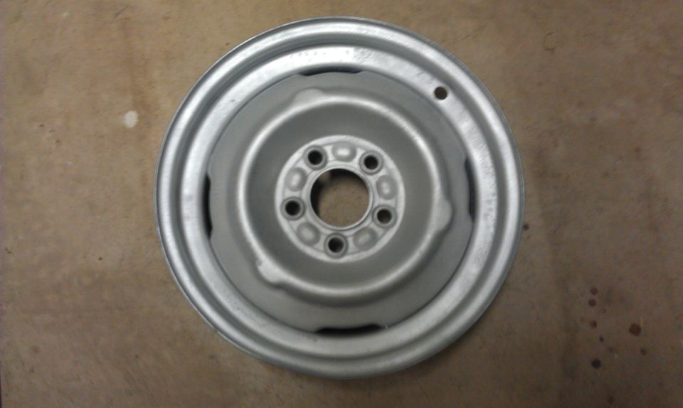 Silver steel wheel with five lug holes and a raised center