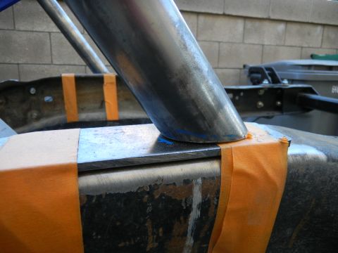 1997 Ford Ranger - Close-up of a fabricated roll bar leg notched and mocked up against a flat steel mounting plate laid on the truck's frame rail, with orange…