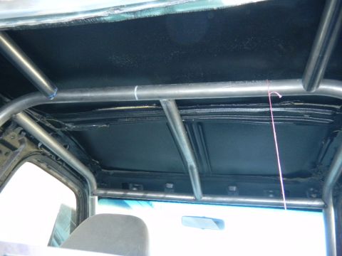 1997 Ford Ranger - Interior view up into the rear of a pickup cab showing a welded tube roll cage with a rear harness/support bar and diagonal braces tucked a…