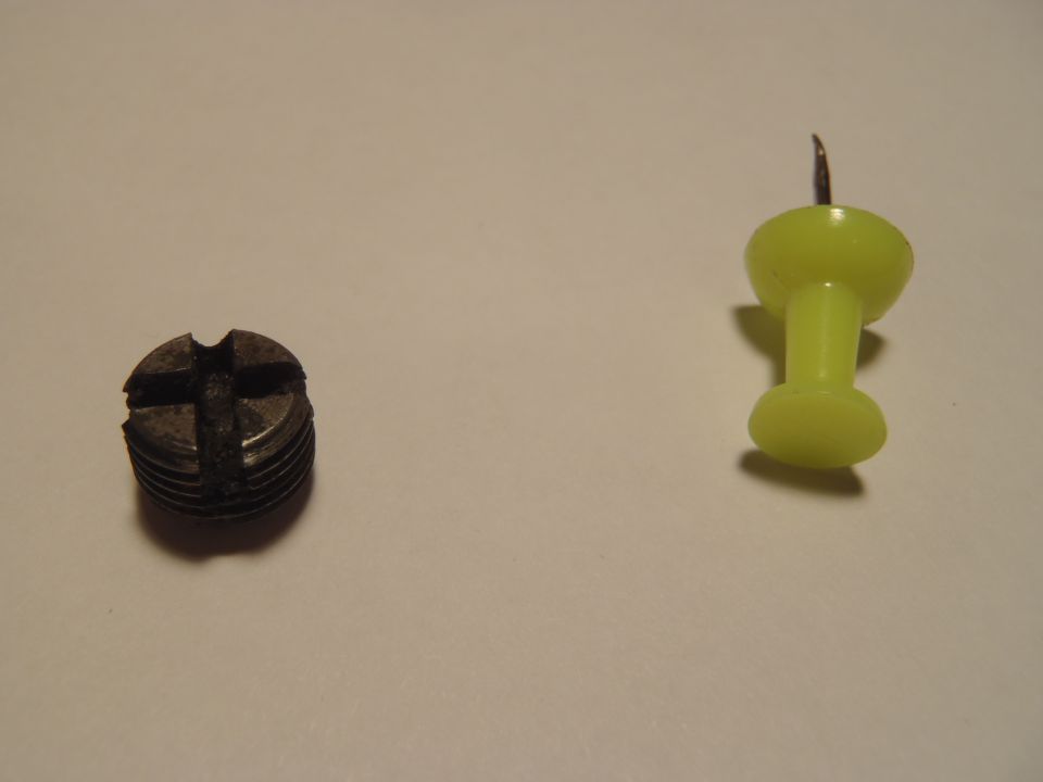 Screw next to a yellow thumbtack