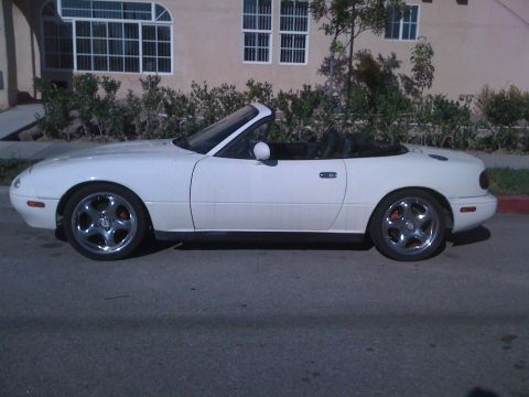 1991 Mazda Miata - This white 1991 Mazda Miata convertible is shown from the side, parked on a street.