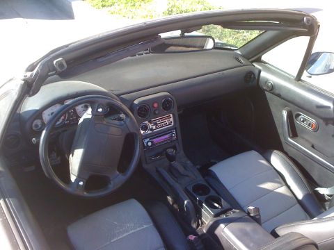 1991 Mazda Miata - The interior of a convertible sports car, showing the dashboard, seats, and center console.