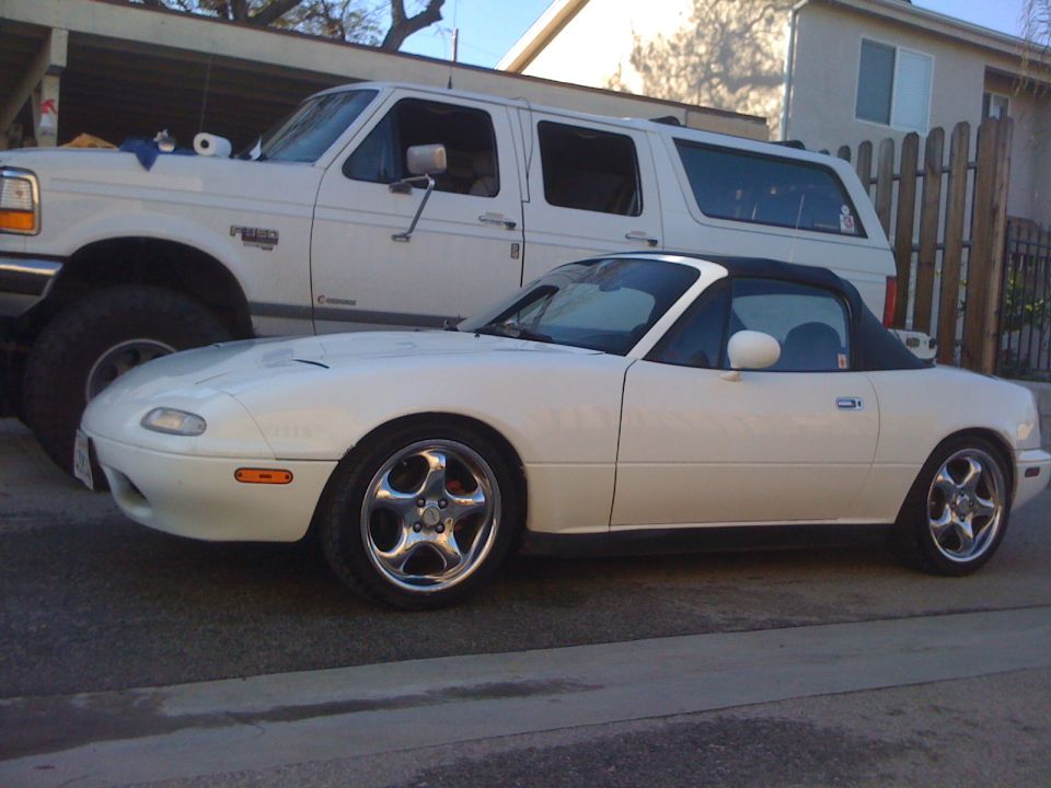 White convertible sports car parked next to a white SUV