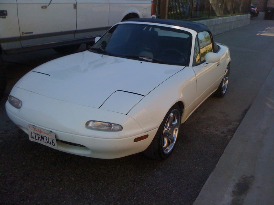 White 1991 Mazda Miata with black soft top and pop-up headlights