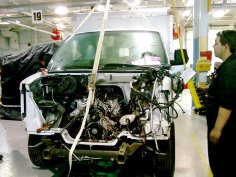 1989 Ford Bronco - A white van is undergoing repairs with its engine completely removed and the front end disassembled.