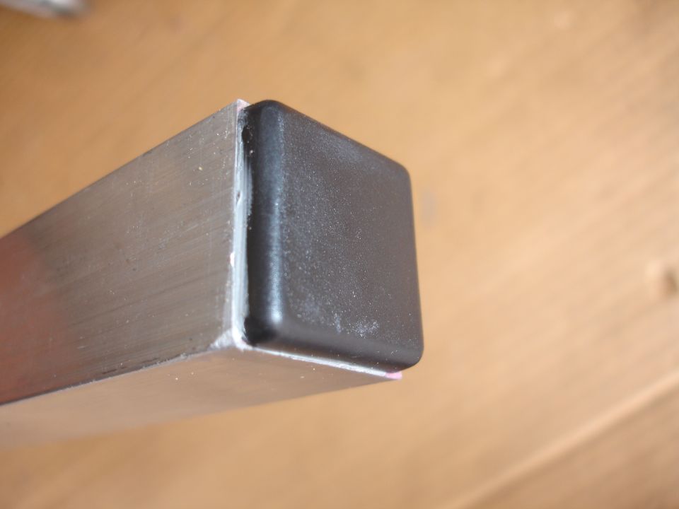 Close-up of a metal tube with a black plastic cap on the end