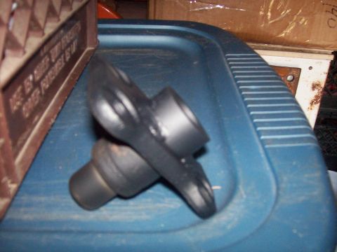 1982 Ford F-100 - A black rubber part rests on a blue plastic surface. Text is visible on a brown object to the left.