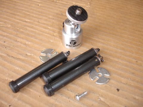 1993 Ford Taurus - A silver camera mount with a black top sits next to three black legs and two metal washers on a wooden surface.