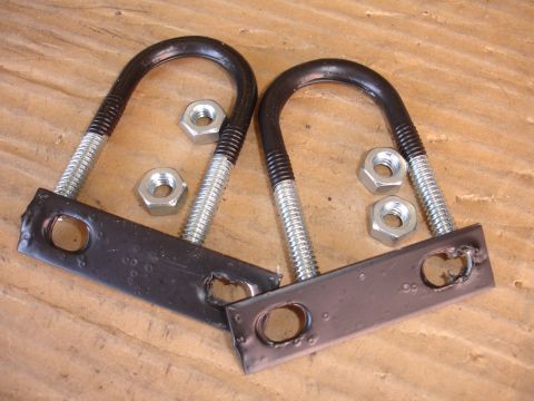 1993 Ford Taurus - Two U-bolts and four nuts are shown on a wooden background.