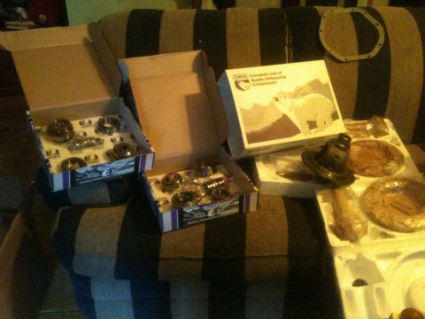 1993 Ford Bronco - Boxes of differential components are laid out on a striped couch, some open to reveal parts.