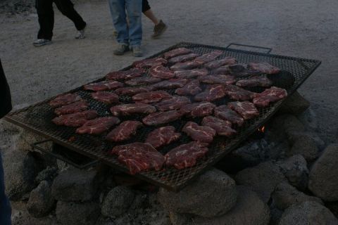 1987 Ford Bronco - Outdoor grilling scene with numerous raw steaks spread across a large metal grate.