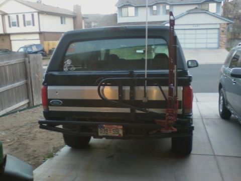 1995 Ford Bronco - Rear view of a black Ford Bronco with a silver stripe and a mounted Hi-Lift jack.