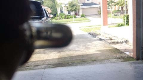 1994 Ford Bronco - A close-up shot focuses on a vehicle's headlight bulb, with a blurred SUV and residential background.