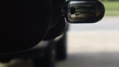 1994 Ford Bronco - A light bulb is held by a gloved hand, with a blurred vehicle in the background.