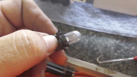 1994 Ford Bronco - A hand holds a small instrument cluster bulb, likely for replacement.