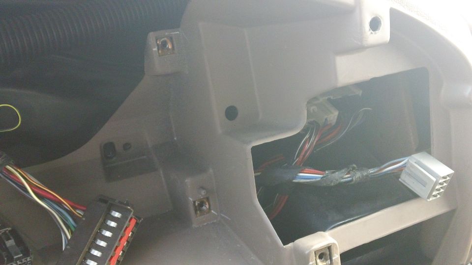 Vehicle interior showing exposed wiring harness and connectors behind dashboard panel