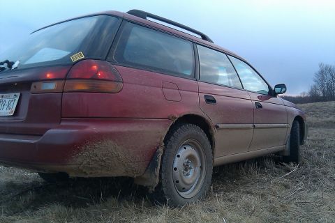 1998 Subaru Legacy - This 1998 Subaru Legacy wagon is seen from the rear, heavily covered in mud, suggesting it has been driven off-road.