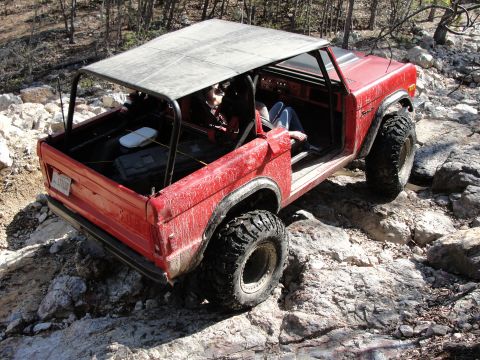 1967 Ford Mustang - This red SUV is equipped for off-road adventures, with its large tires and roll cage clearly visible as it traverses a rocky path.