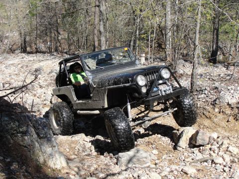 1967 Ford Mustang - A black Jeep Wrangler navigates a challenging rocky terrain on an off-road trail.