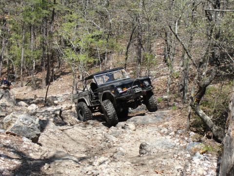 1967 Ford Mustang - A black Ford Bronco tackles a challenging rocky path during an off-road event.