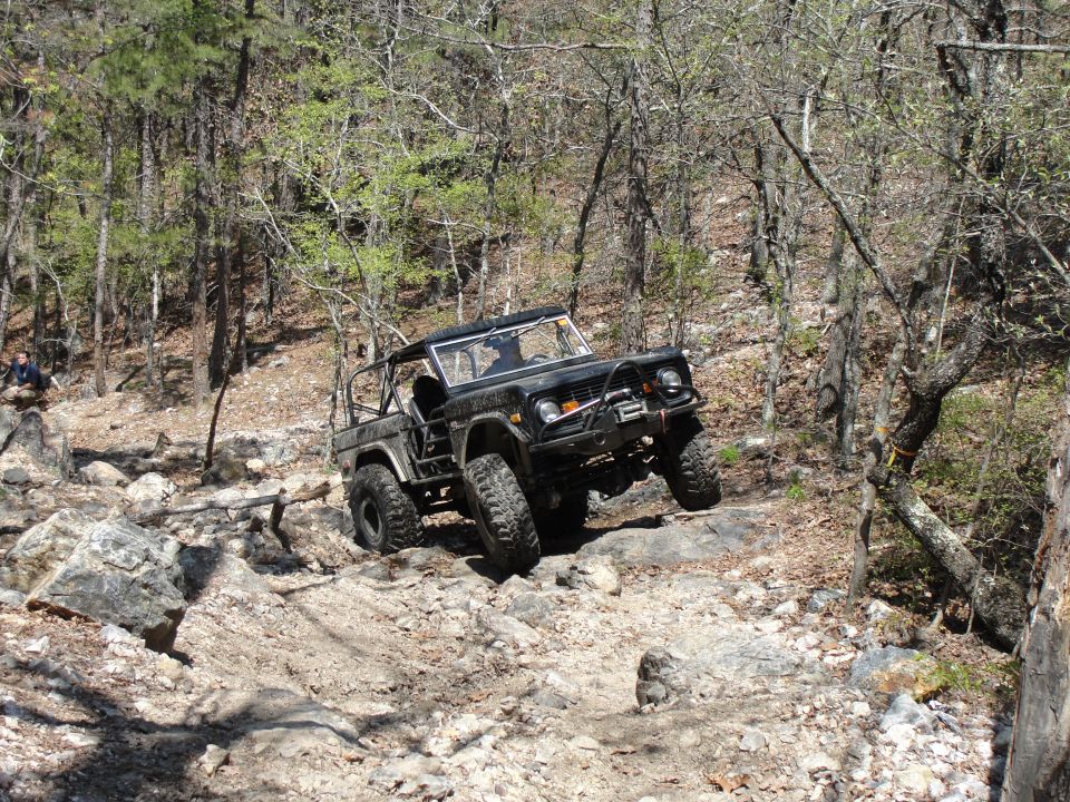 Black 1975 Ford Bronco off-roading on a rocky trail