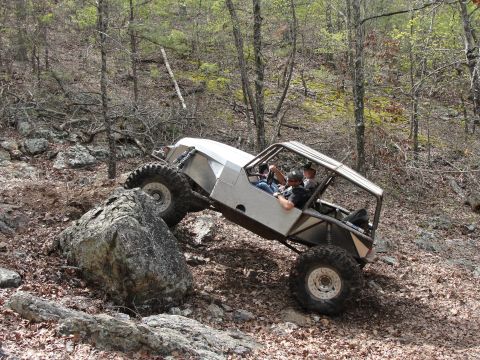 1967 Ford Mustang - A custom-built off-road vehicle navigates a rocky incline in a wooded area.