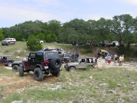 1973 Ford Bronco - A group of off-road vehicles gathered on a hillside during an outdoor event.