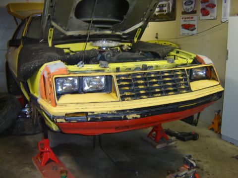 1979 Ford Mustang - Front view of a 1979 Ford Mustang with its hood open, elevated on jack stands for maintenance.
