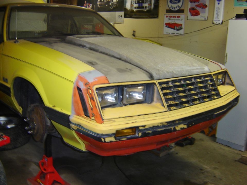 1979 Ford Mustang front end with hood scoop, yellow paint, and orange primer on fender