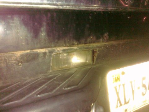 1995 Ford Bronco - Close-up of a vehicle's rear bumper, including a license plate and a reflector light.