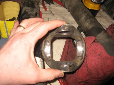 1990 Ford F-250 - A close-up view of a worn driveshaft U-joint, held by a hand over a red rag.