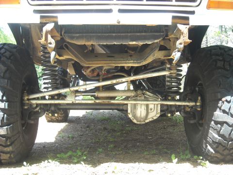 1979 Ford F-150 - The front suspension and steering components of a heavily modified truck are visible from a low angle.